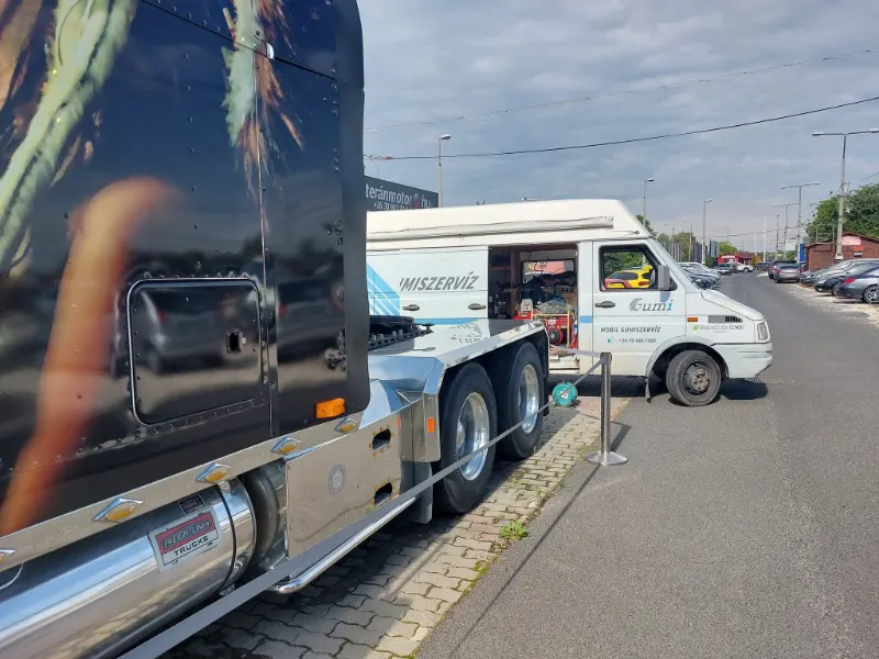Amerikai nyerges vontató mellett dolgozik a mobil gumiszerviz.
